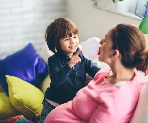 Une femme enceinte et son petit garçon batifolant sur le canapé