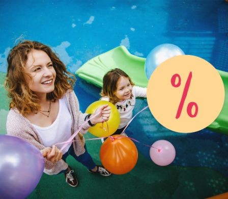 Une maman et sa petite fille avec un ballon de baudruche devant un toboggan