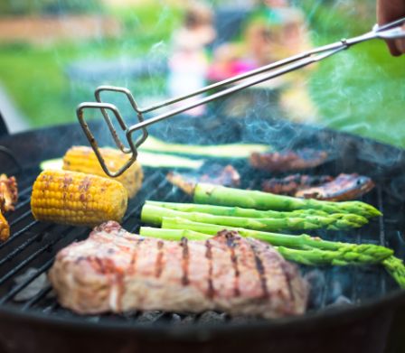 De la viande, des asperges vertes et des épis de maïs sur le gril